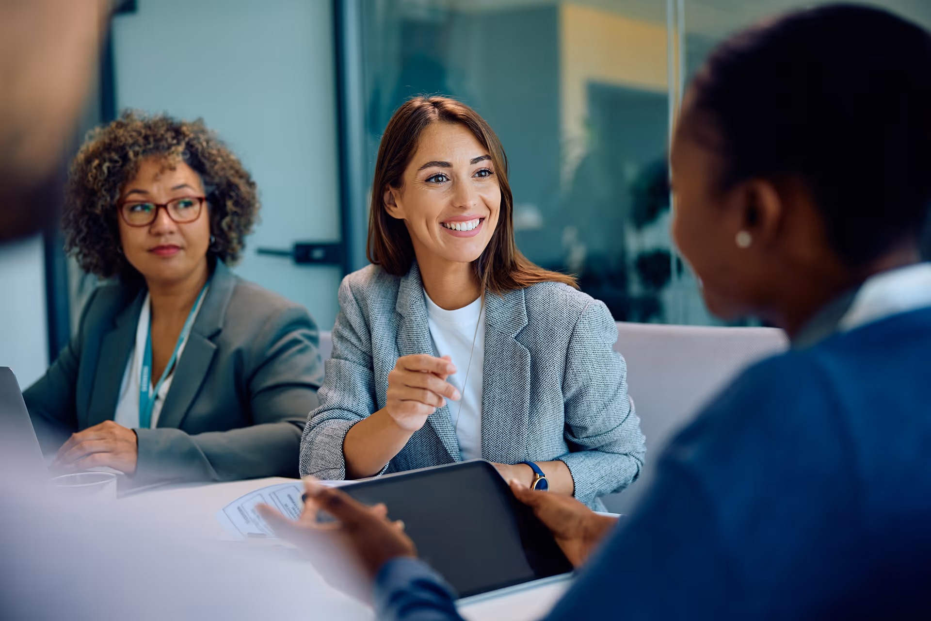 Trois professionnelles en réunion dans un bureau, une femme souriante parle avec ses collègues.